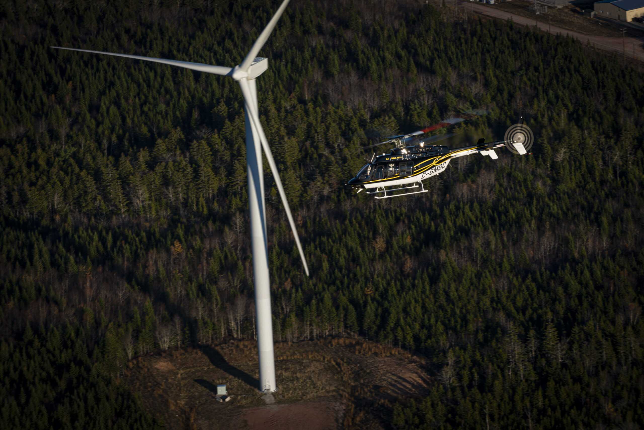 GPMS next-gen HUMS Customer Profile, Municipal Group's Bell 407GXi in flight near windmill. 